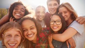 Teenage school friends smiling to camera, close up